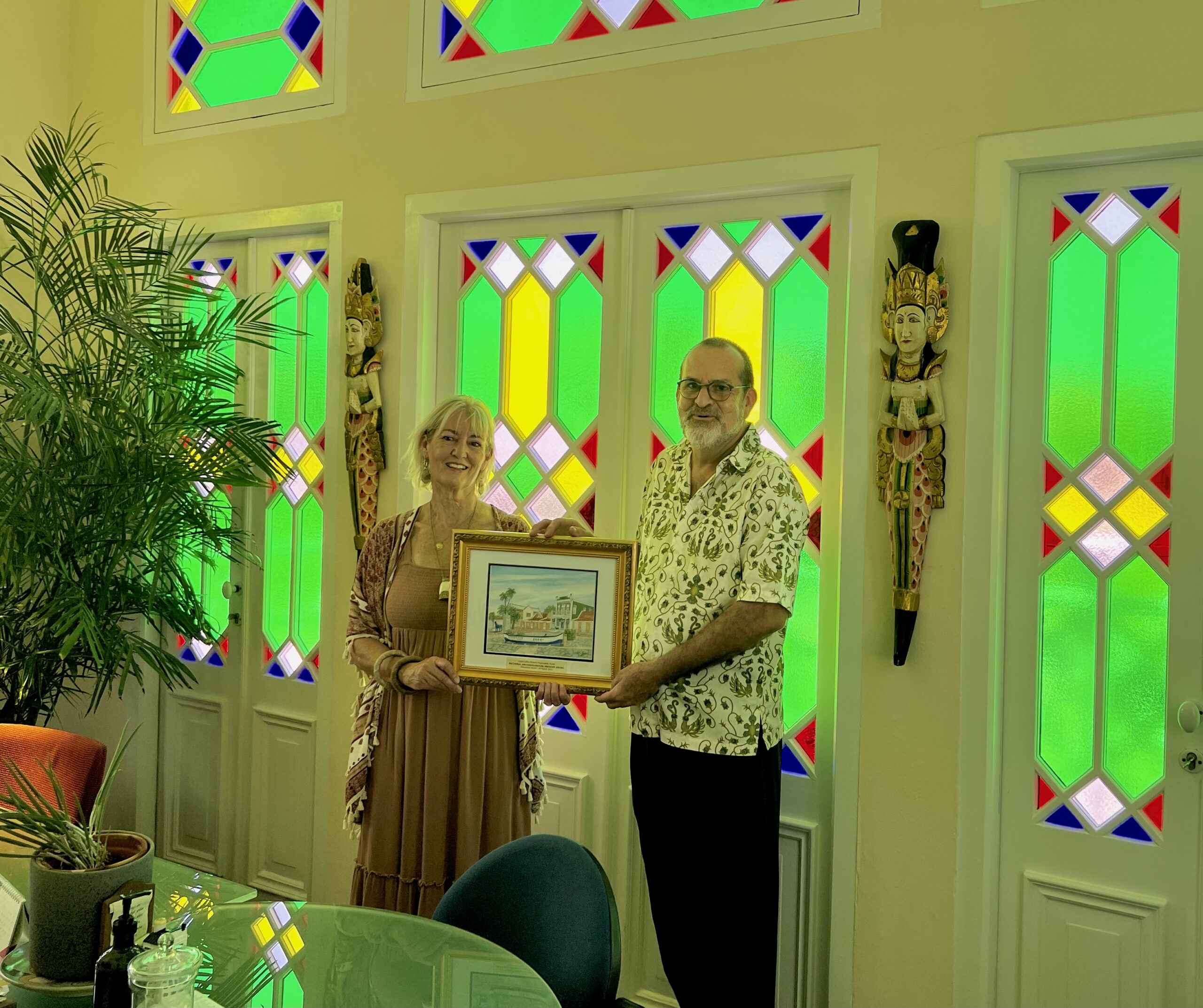 Leisa Collins and Panch Geerman in posing with the award in the office of Mr. Geerman. The stained glass is original to the Ecury Colonial Mansion.
